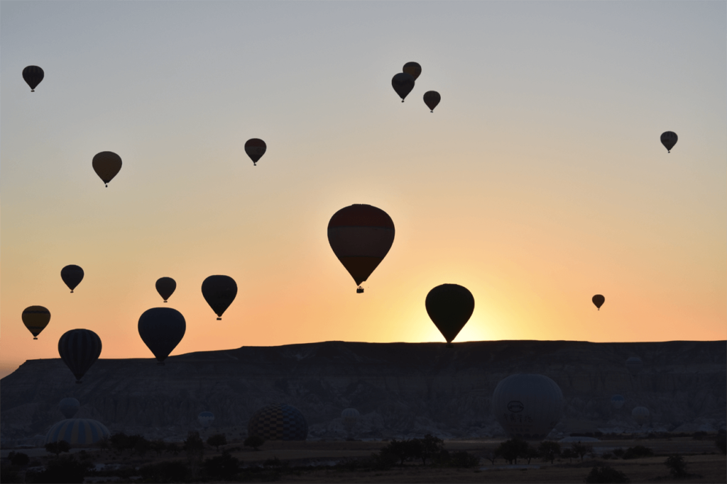 Nascer do sol com céu cheio de balões na Capadócia, Turquia